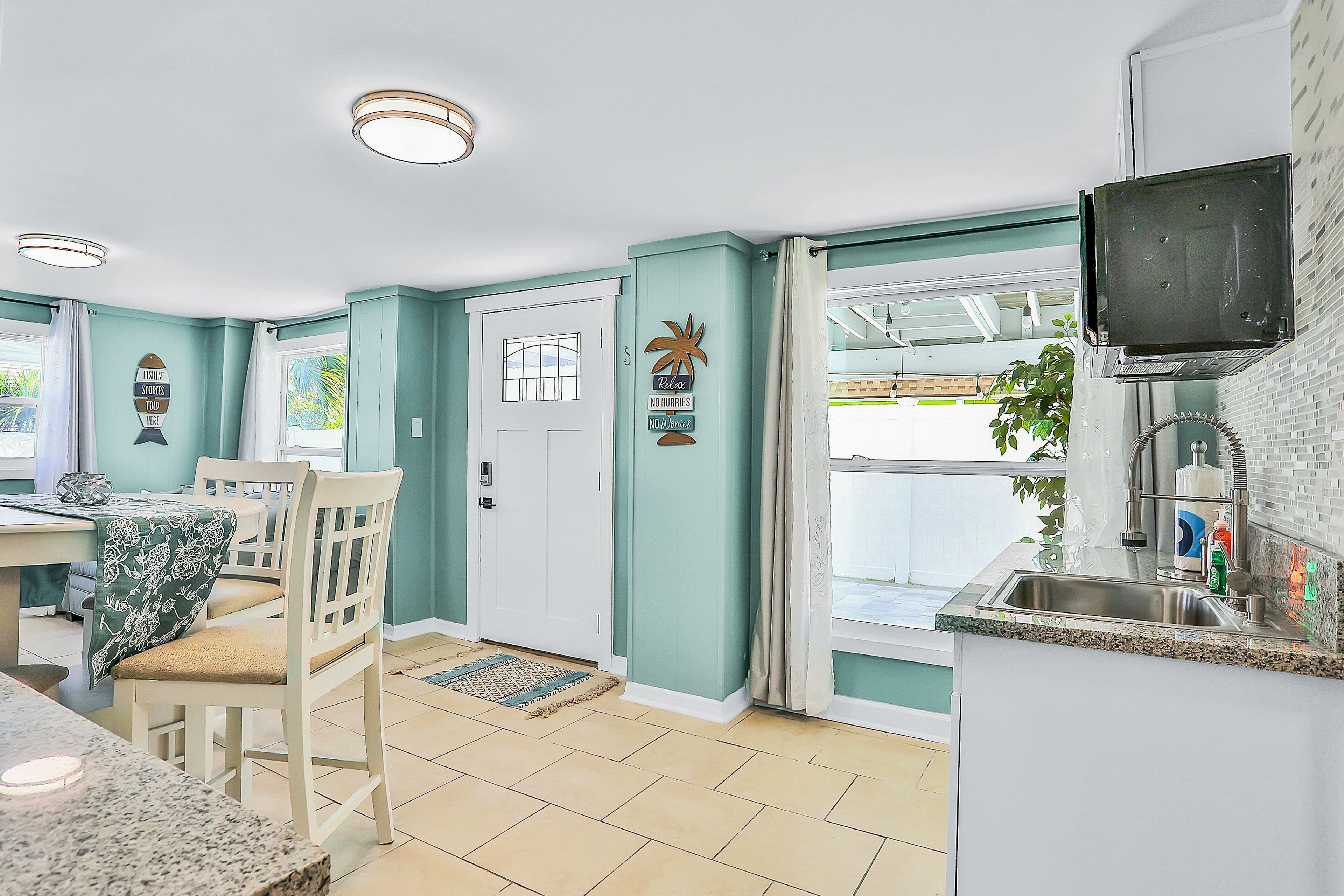 A kitchen with a built-in TV, a dining area with a table and chairs, and a view of the outdoors.