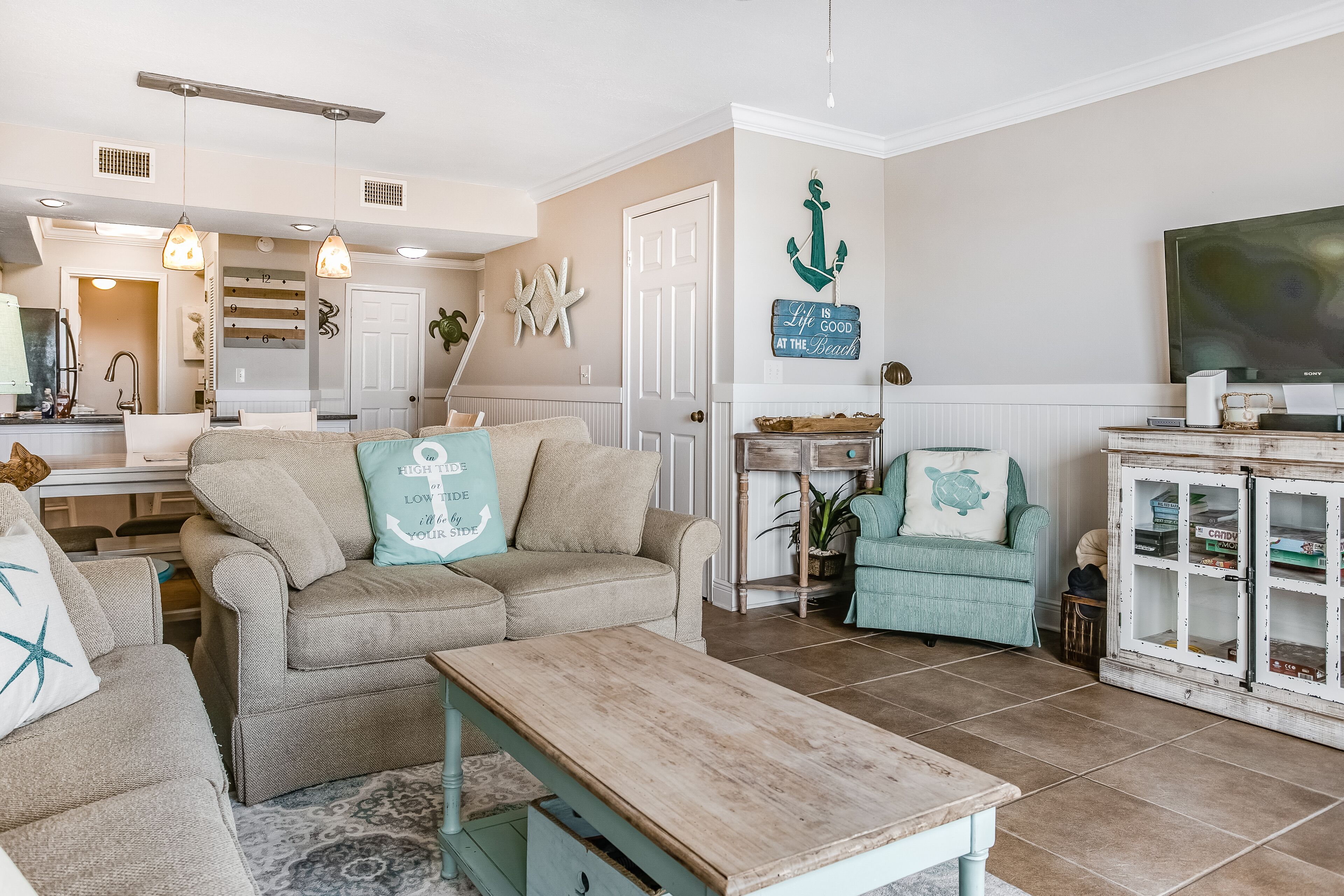 A living room with a sofa, a coffee table, a television, and a cabinet with decorative items.