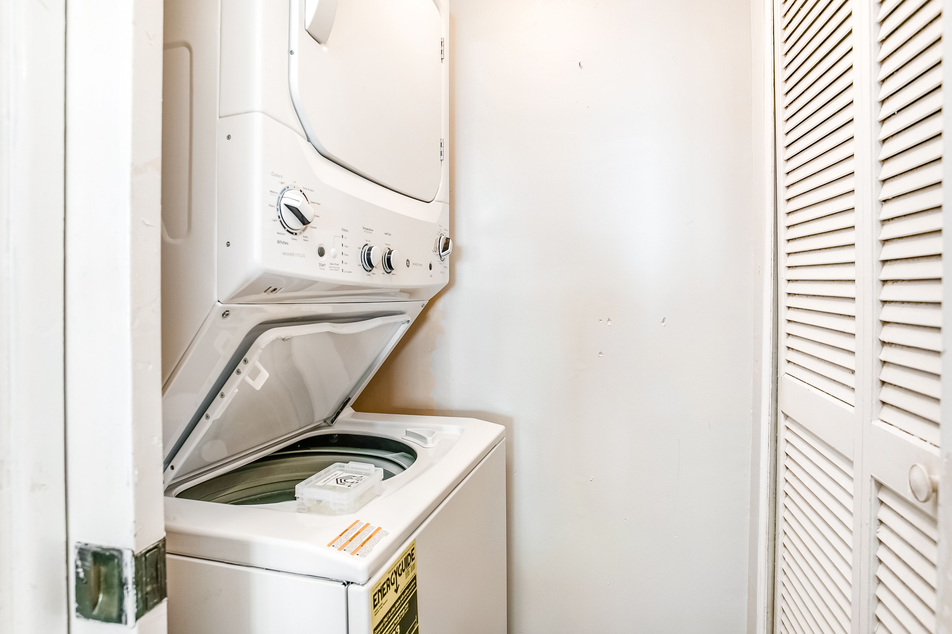 A front-loading washing machine with an ENERGY GUIDE label, a control panel with various settings, and a door with a handle.