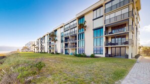 A multi-story hotel with balconies, large windows, and a grassy area in front. - First Floor Oceanfront Condo With Beach Access and Tennis Courts (St. Augustine)