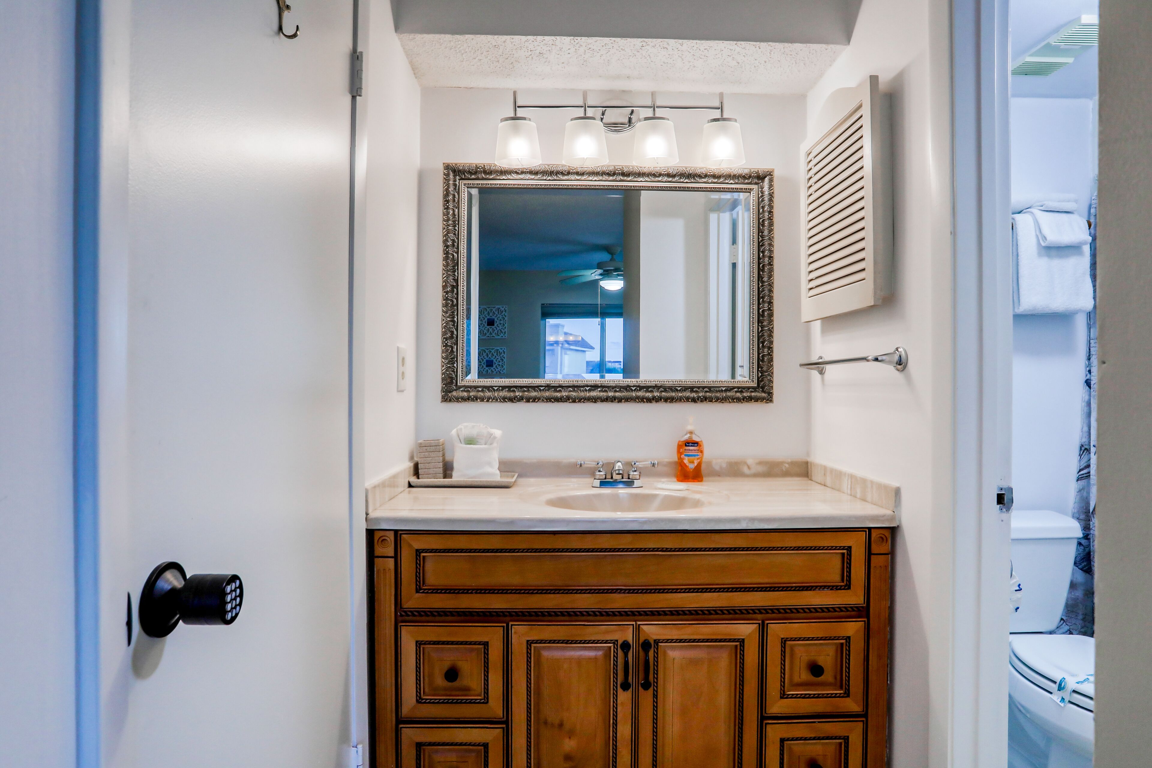 A bathroom with a wooden vanity, a large mirror, and a sink.