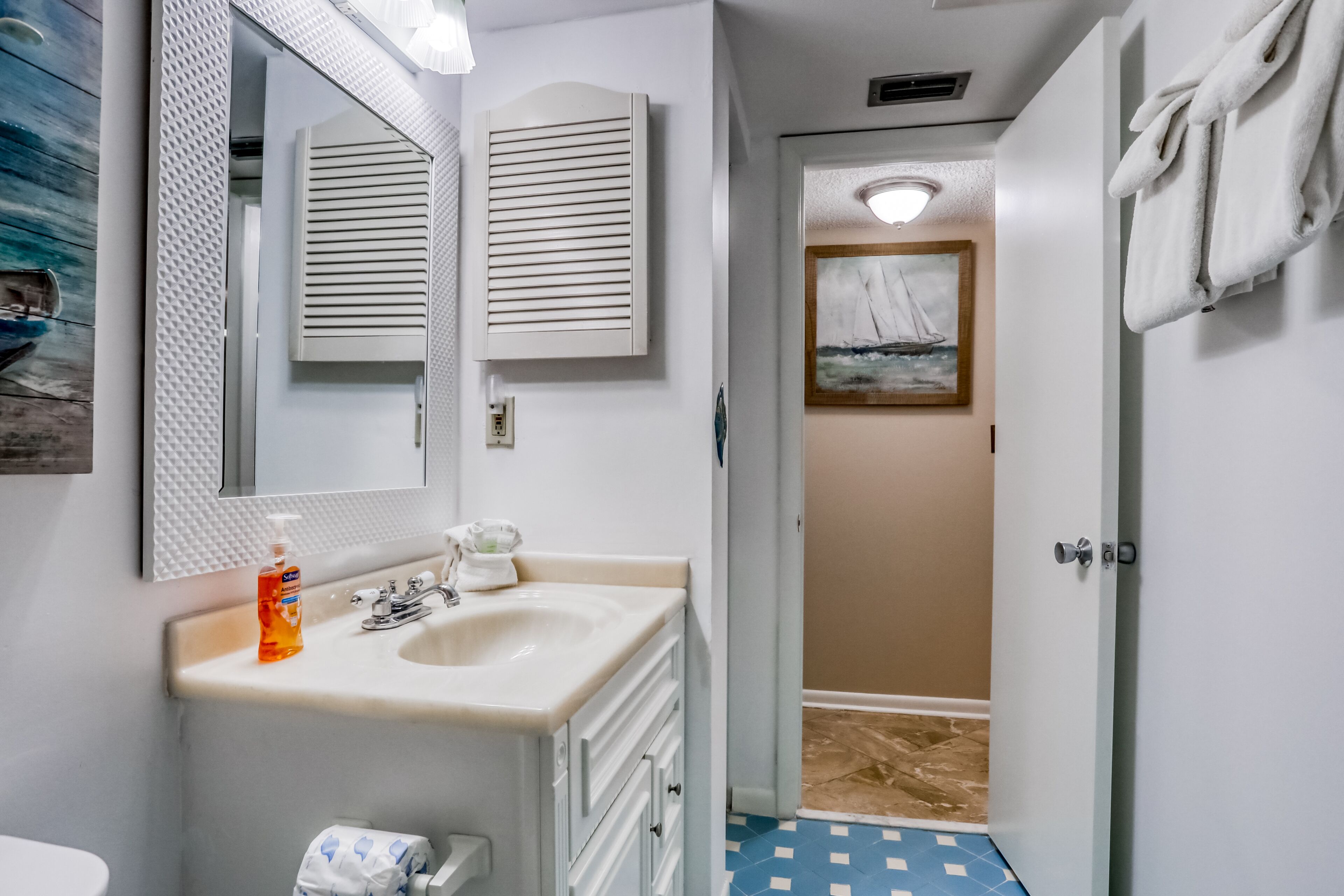 A bathroom with a sink, mirror, and towel rack.
