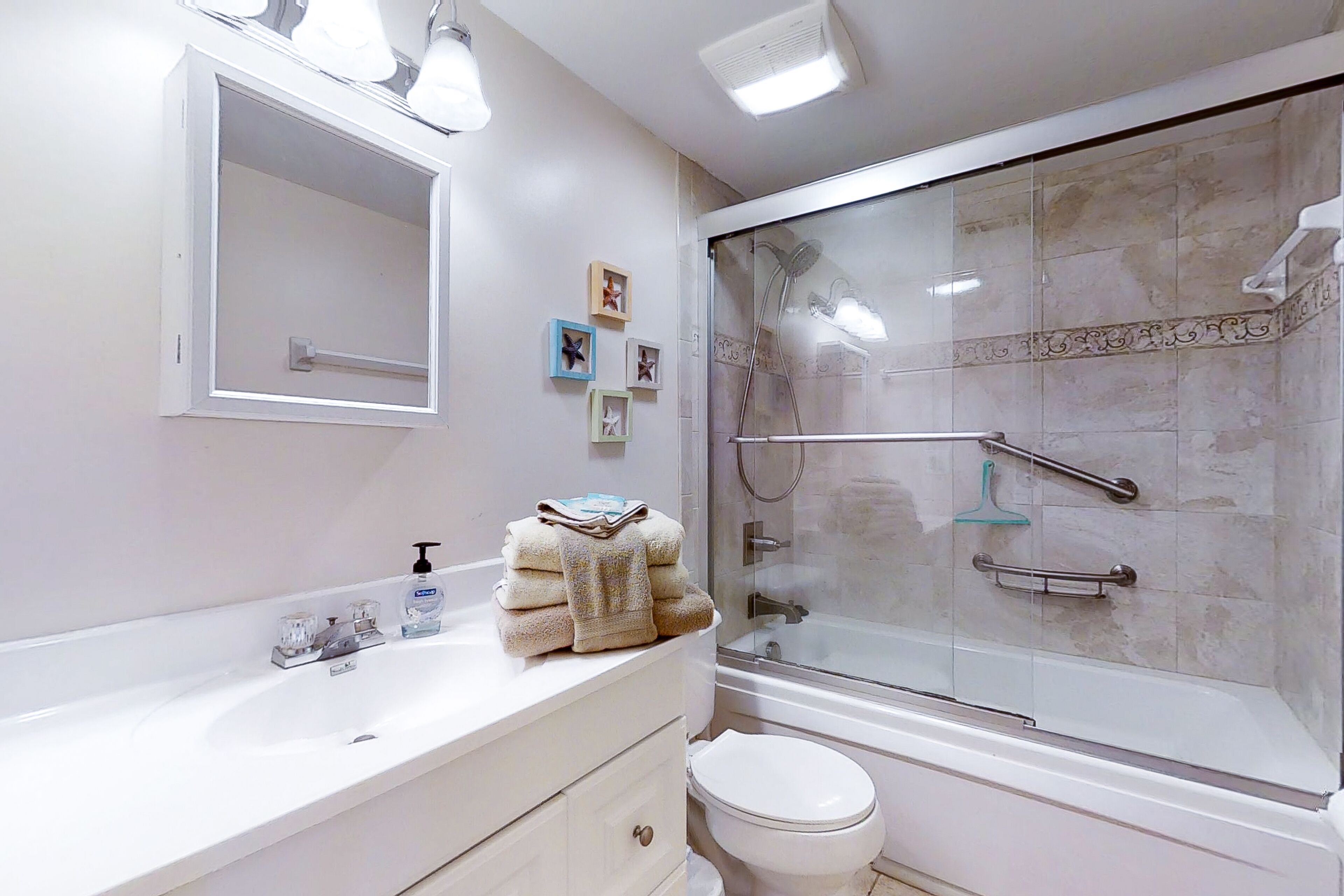 A modern bathroom with a glass-enclosed shower, a white sink with a mirror above it, and a toilet.