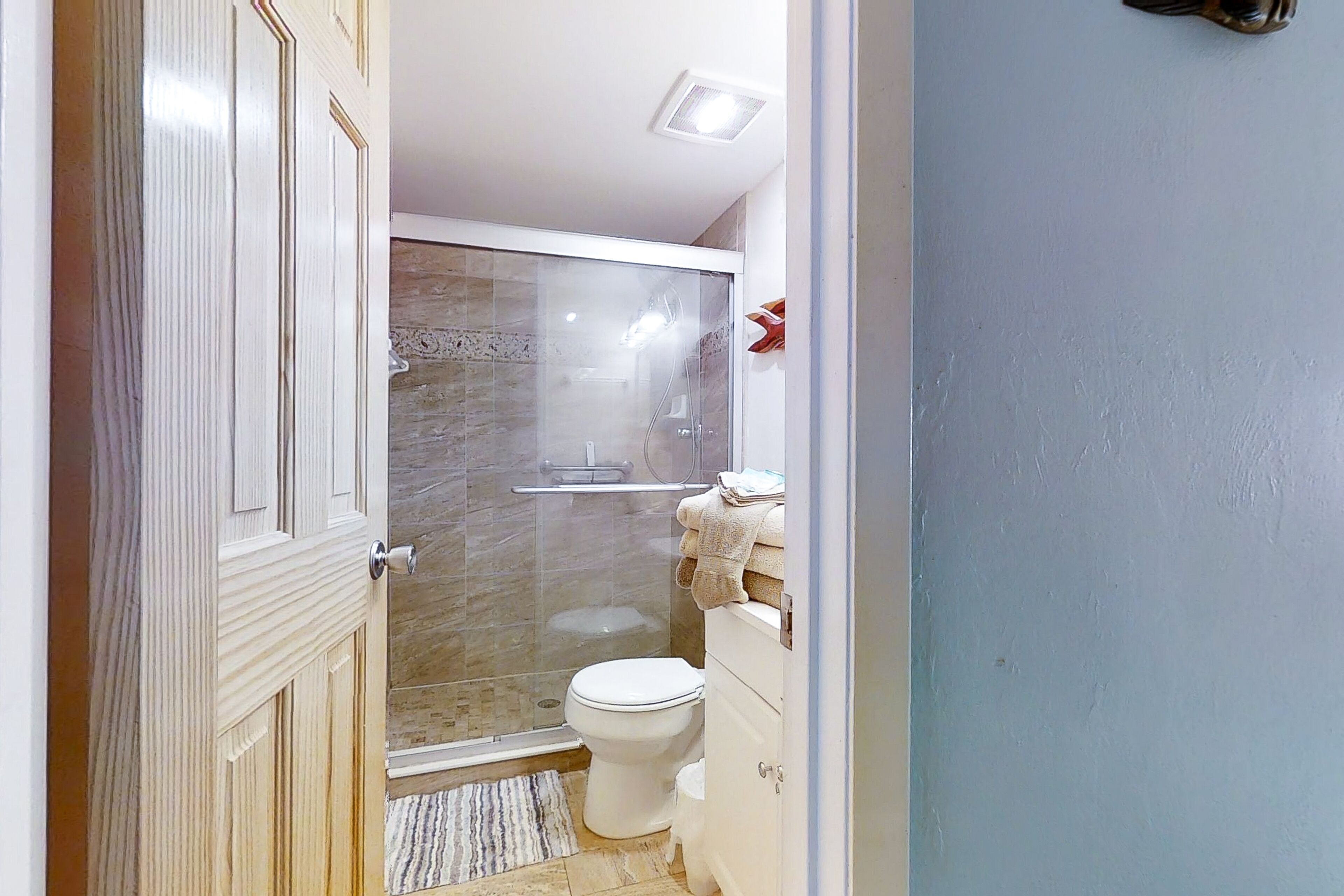 Une salle de bain avec une douche à parois de verre, des toilettes et un lavabo.