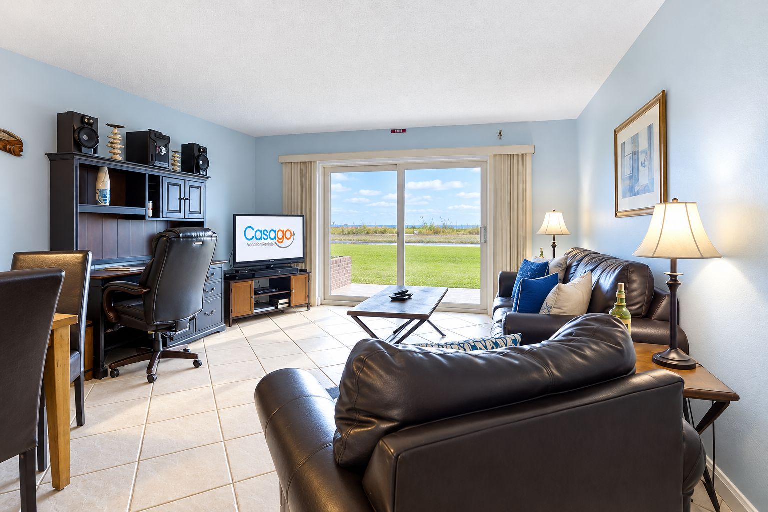 A living room with a television, a sofa, a coffee table, and a desk with a computer.