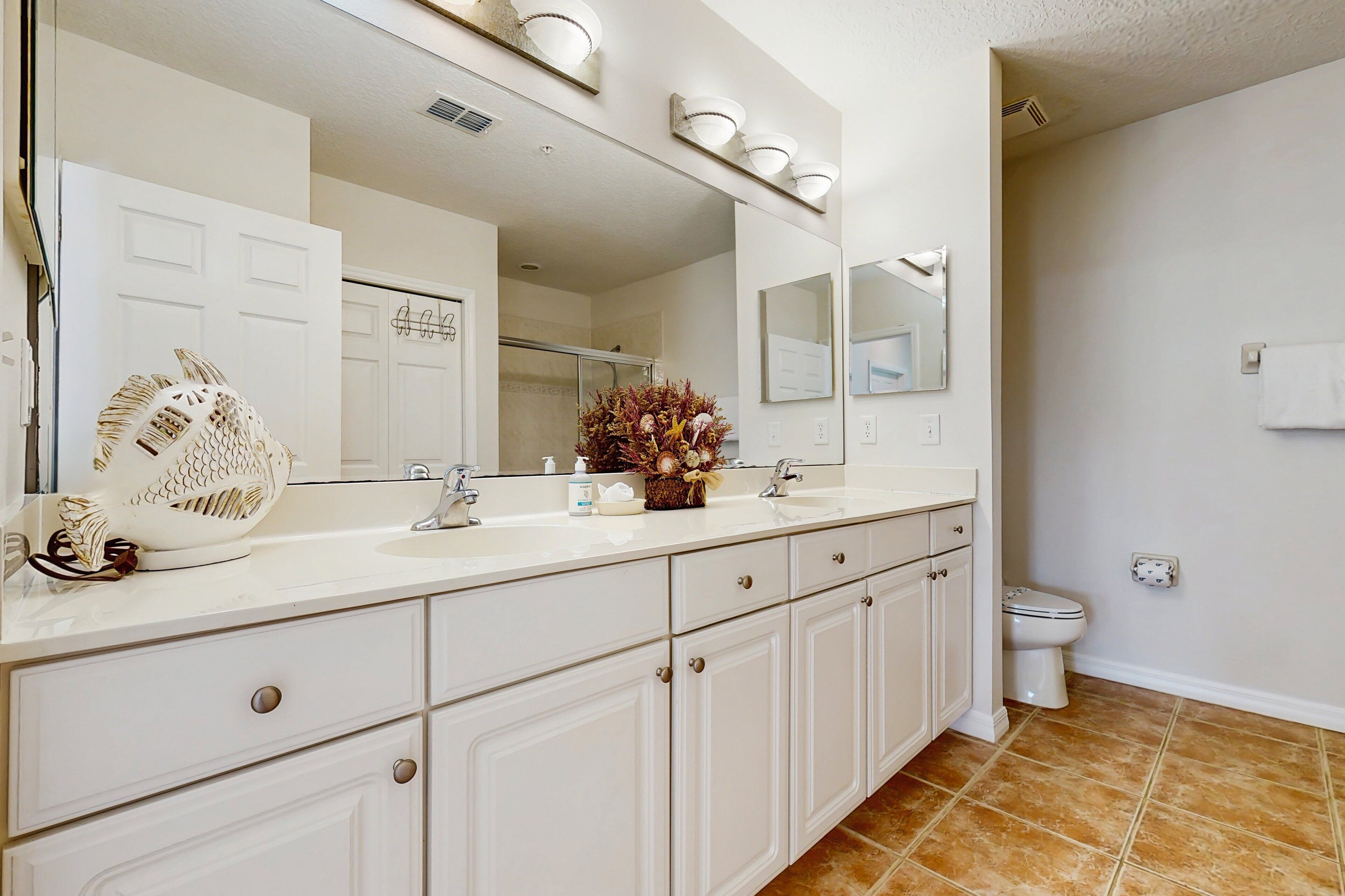 A bathroom with a white vanity, a large mirror, and a toilet.