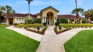 Una casa de dos pisos con techo de tejas rojas, fachada amarilla y un acceso central con un amplio arco.