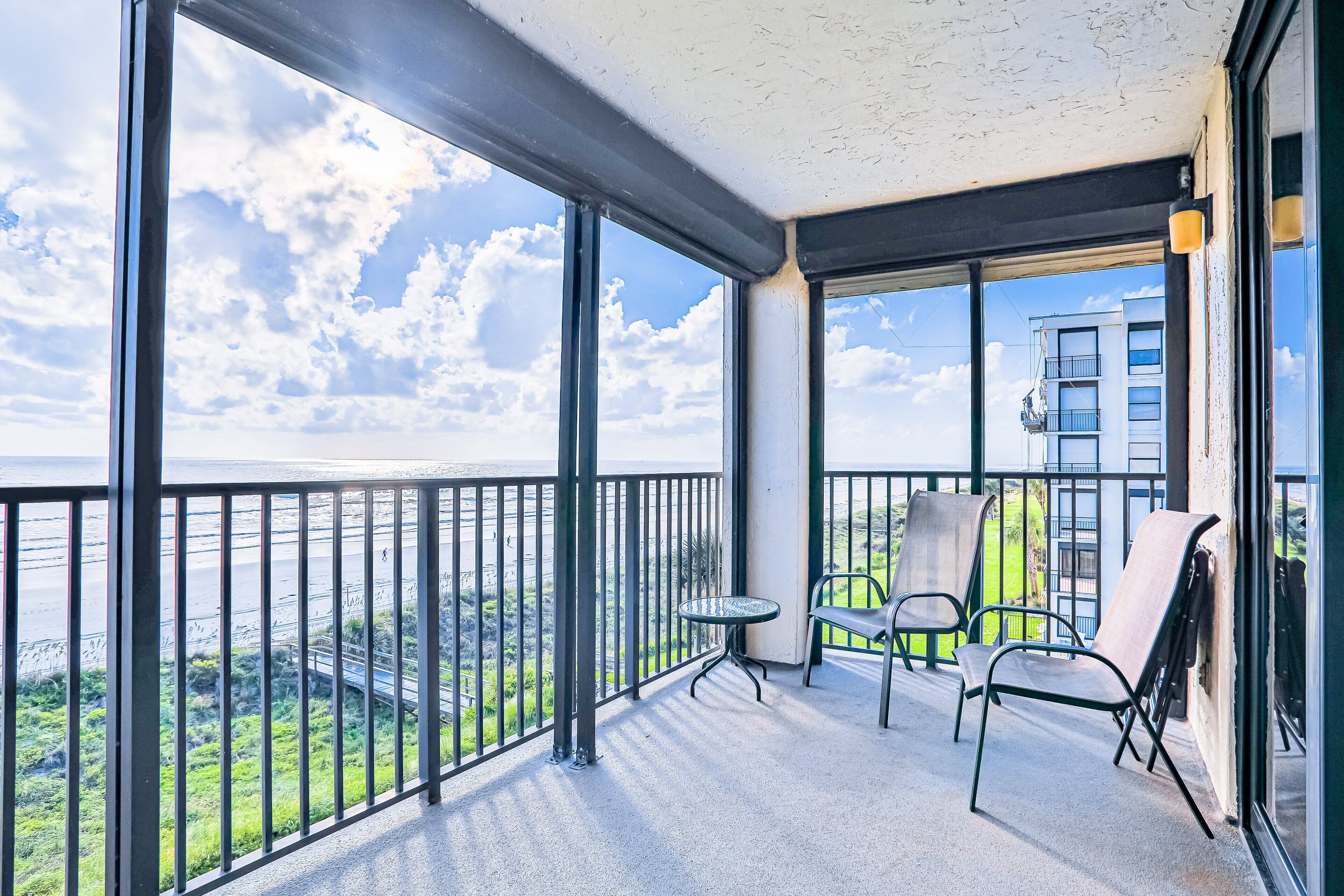 A balcony with a glass railing, a small round table, and two chairs.