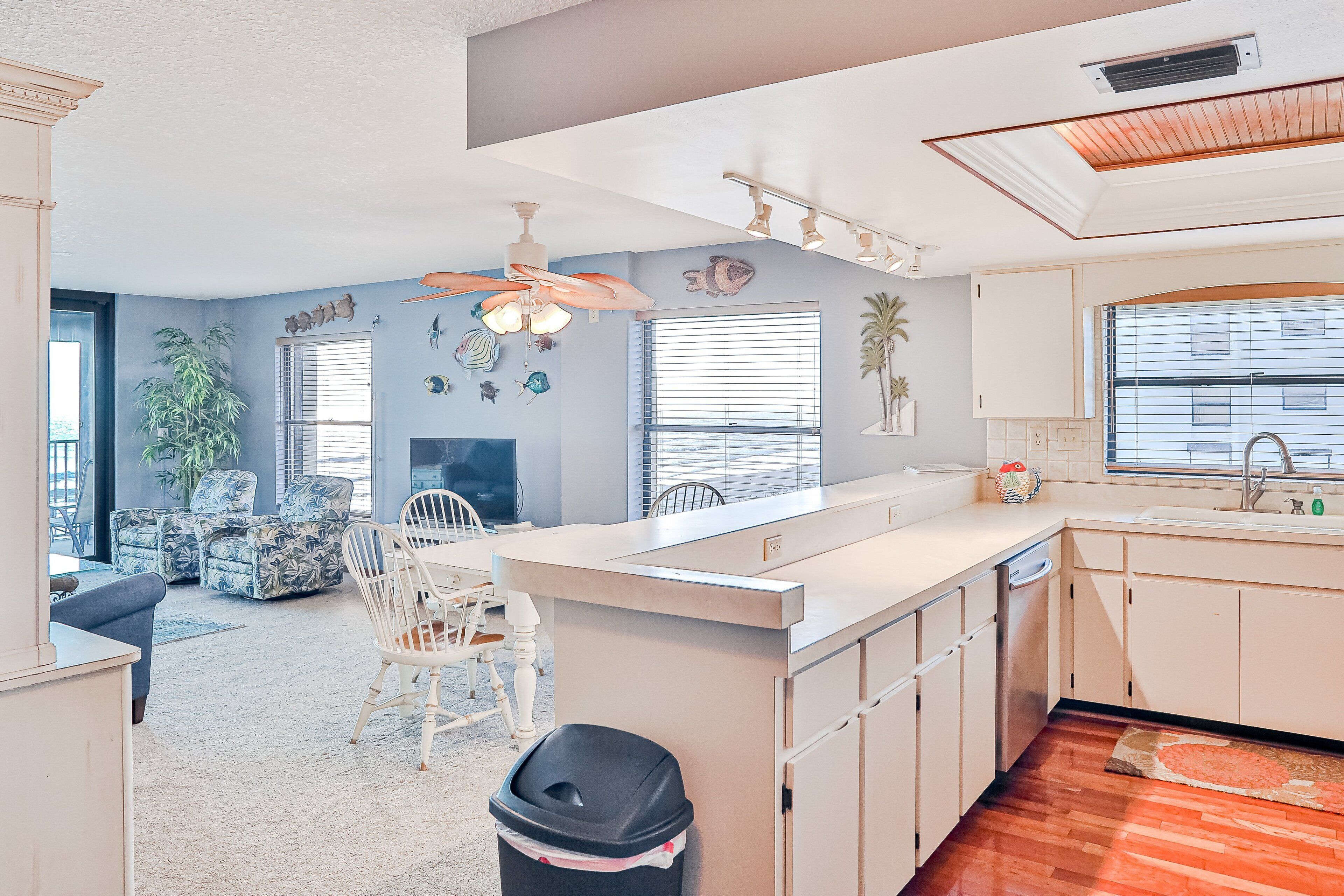 A modern kitchen with a central island, white cabinetry, and a dining area with a white table and chairs.