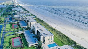 Ein Luftbild eines an der Küste gelegenen Hotels mit mehreren Gebäuden, einem Strand und einem Schwimmbad.