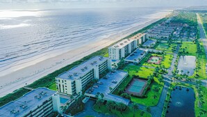 Ein Hotel an der Küste mit mehreren Gebäuden, einem Strand und einem Golfplatz.