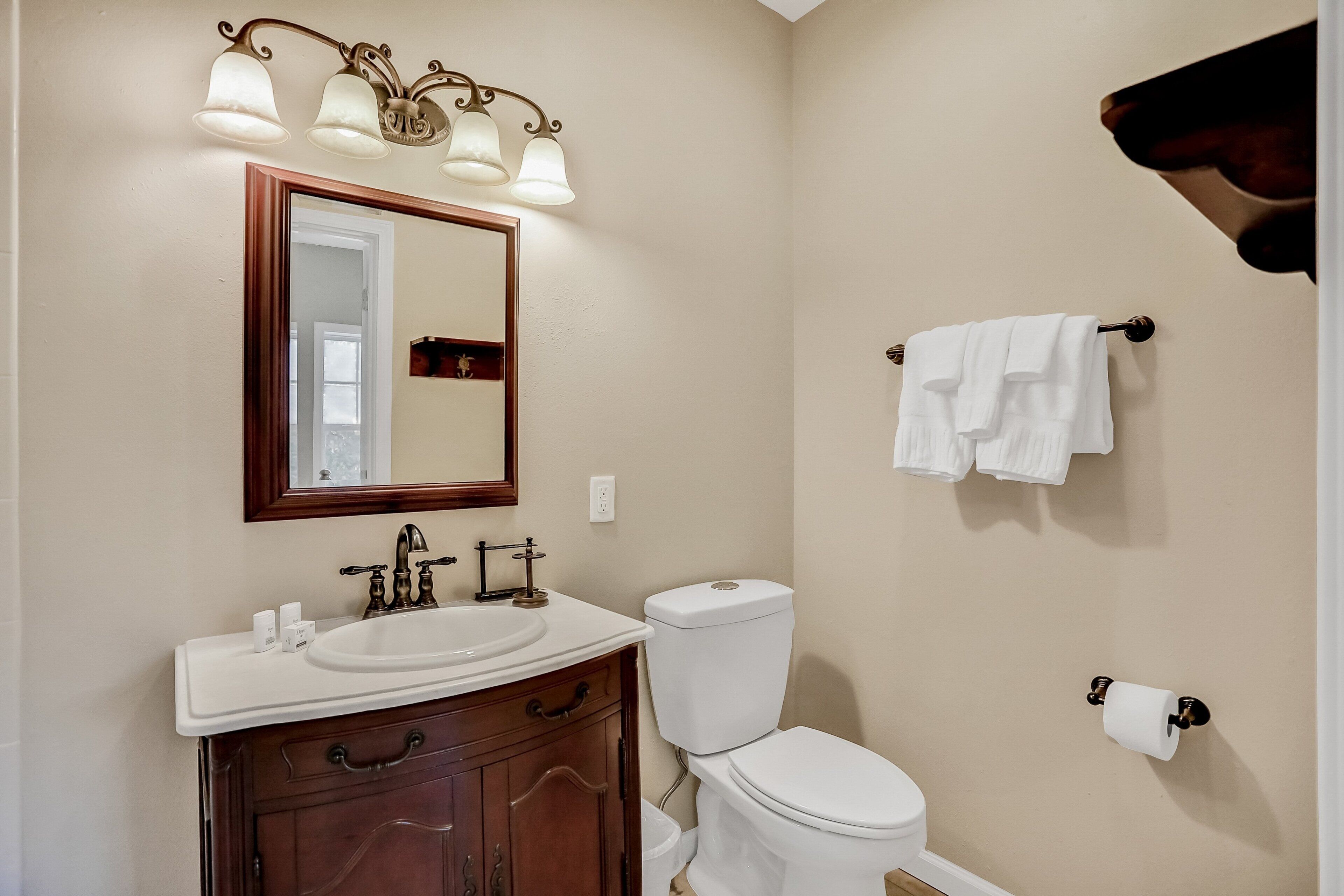 A bathroom with a sink, mirror, toilet, and towel rack.