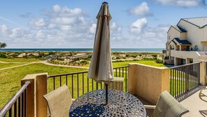 Un balcone con tavolo e sedie, vista sulla spiaggia e sull'oceano.