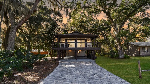 A two-story house with a covered porch, surrounded by trees and a brick pathway. - Family & Pet-friendly Home Near Beach, Downtown & Boat Ramp (St. Augustine)