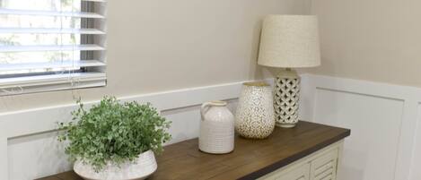 A kitchen counter with a potted plant, a white pitcher, and a patterned lamp.