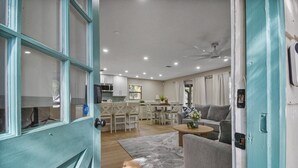A modern living room with a sofa, coffee table, and a dining area with chairs and a table. - Family & Pet-friendly Home Near Beach, Downtown & Boat Ramp (St. Augustine)