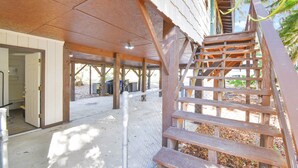 A wooden staircase leading to a covered outdoor area with a metal fence and a door to a building. - Family & Pet-friendly Home Near Beach, Downtown & Boat Ramp (St. Augustine)