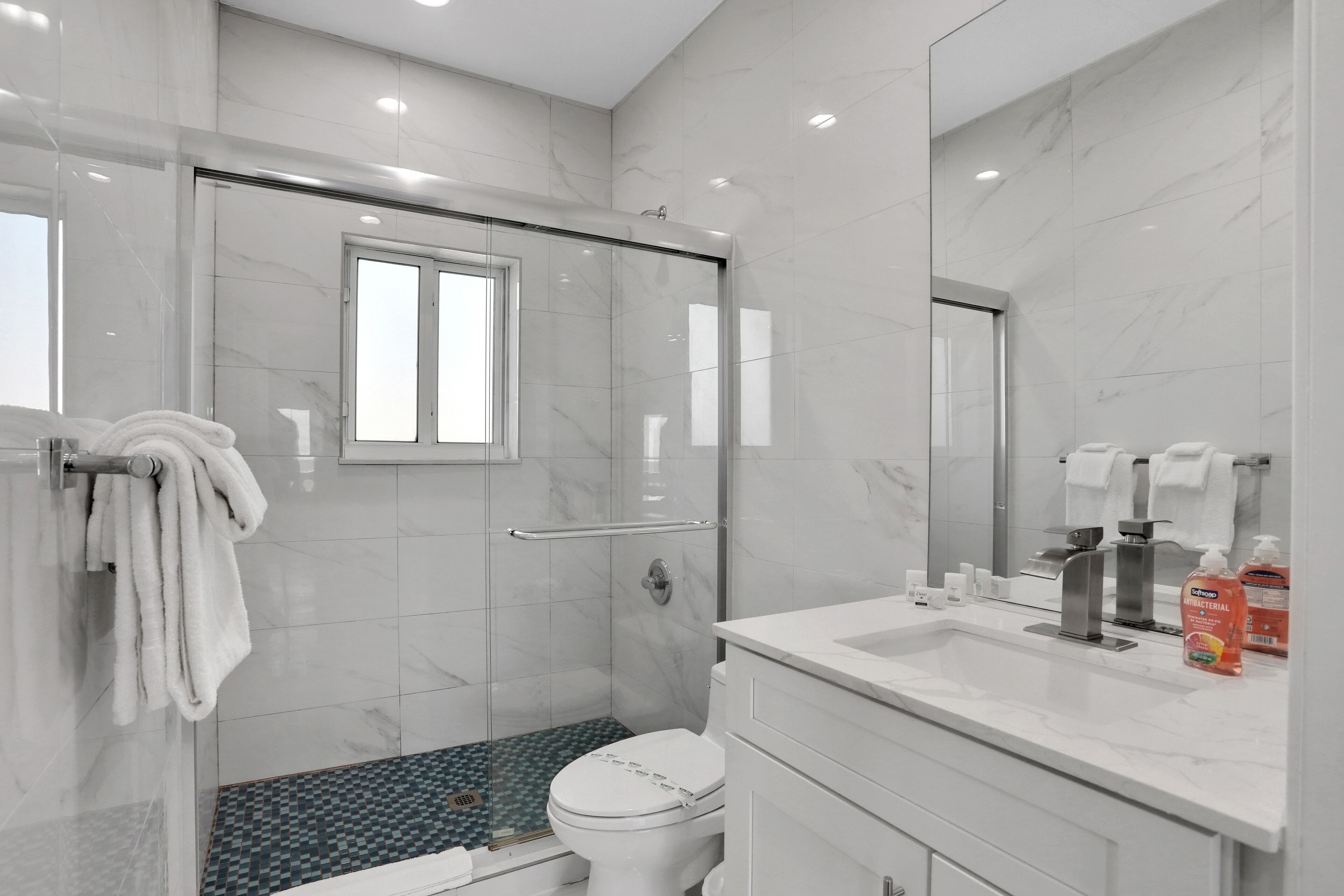 Une salle de bain moderne avec une douche à parois de verre, des toilettes et un lavabo équipé de produits de toilette.