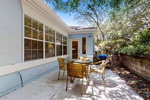 A patio with wicker furniture and a blue door. - Lovely Home in Summer Beach Village - Steps to Beach & Community Pool (Fernandina Beach)