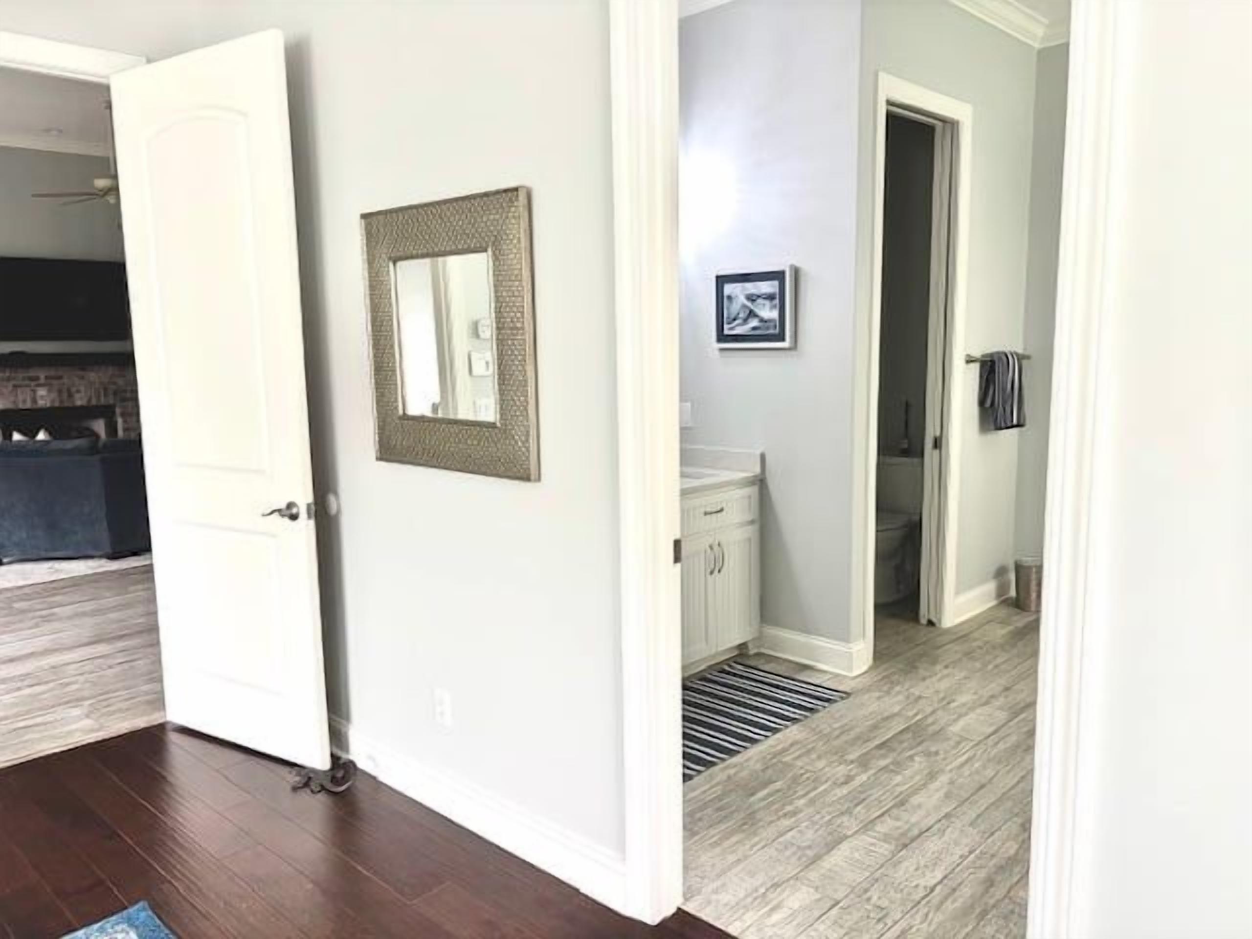 A hallway with a door, a framed picture, a radiator, and a bathroom visible in the background.