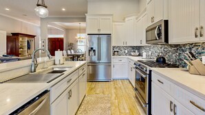 A modern kitchen with white cabinetry, stainless steel appliances, and a tiled backsplash. - Golf Course-view Home Near Beaches With Deck, Porch, Grill, Streaming, W/d, & AC (St. Simons Island)