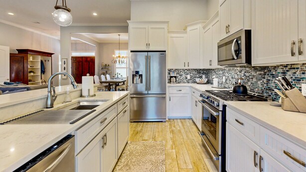 Una cocina moderna con armarios blancos, electrodomésticos de acero inoxidable y un salpicadero de azulejos.
