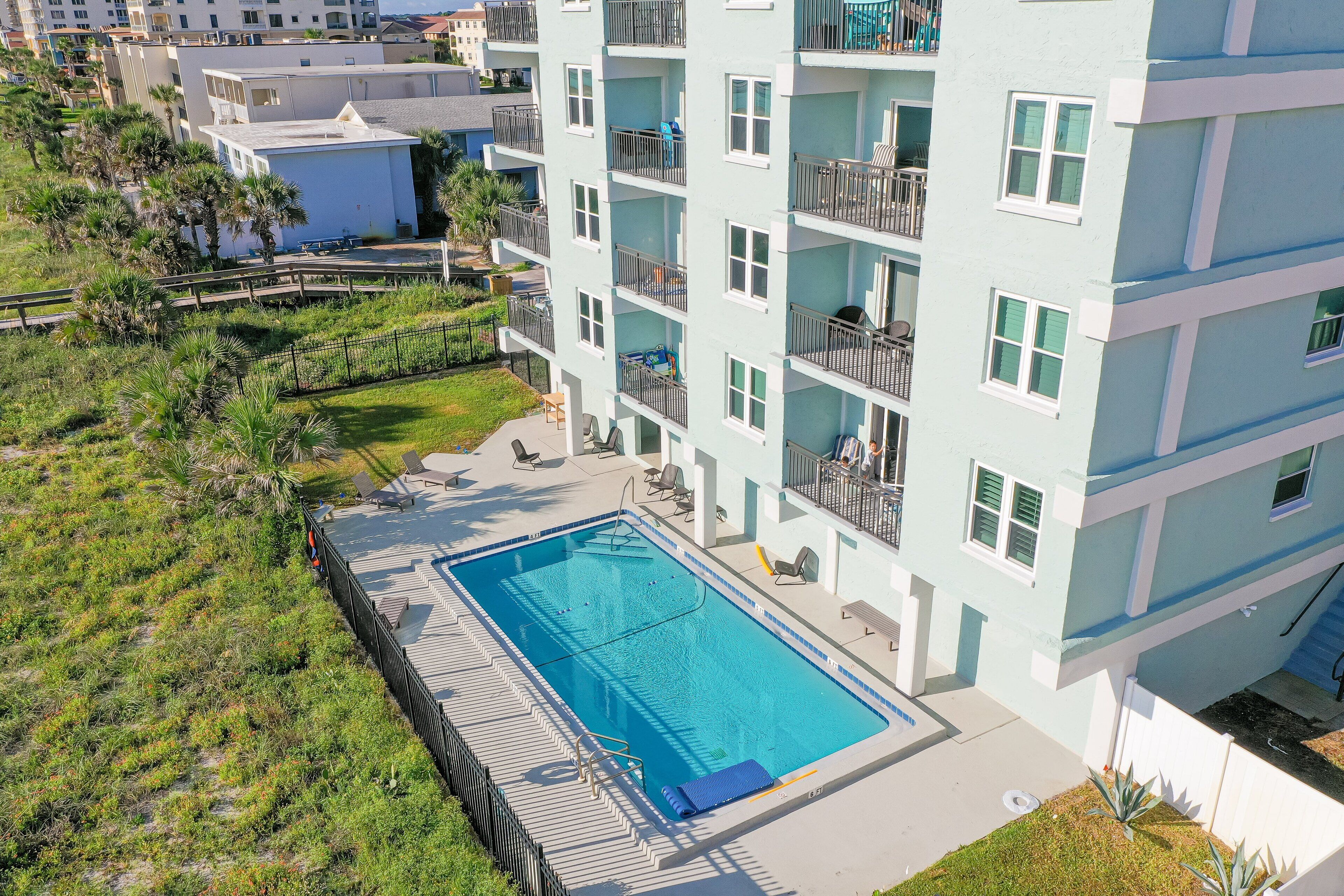 A multi-story hotel with a swimming pool, outdoor seating, and balconies.