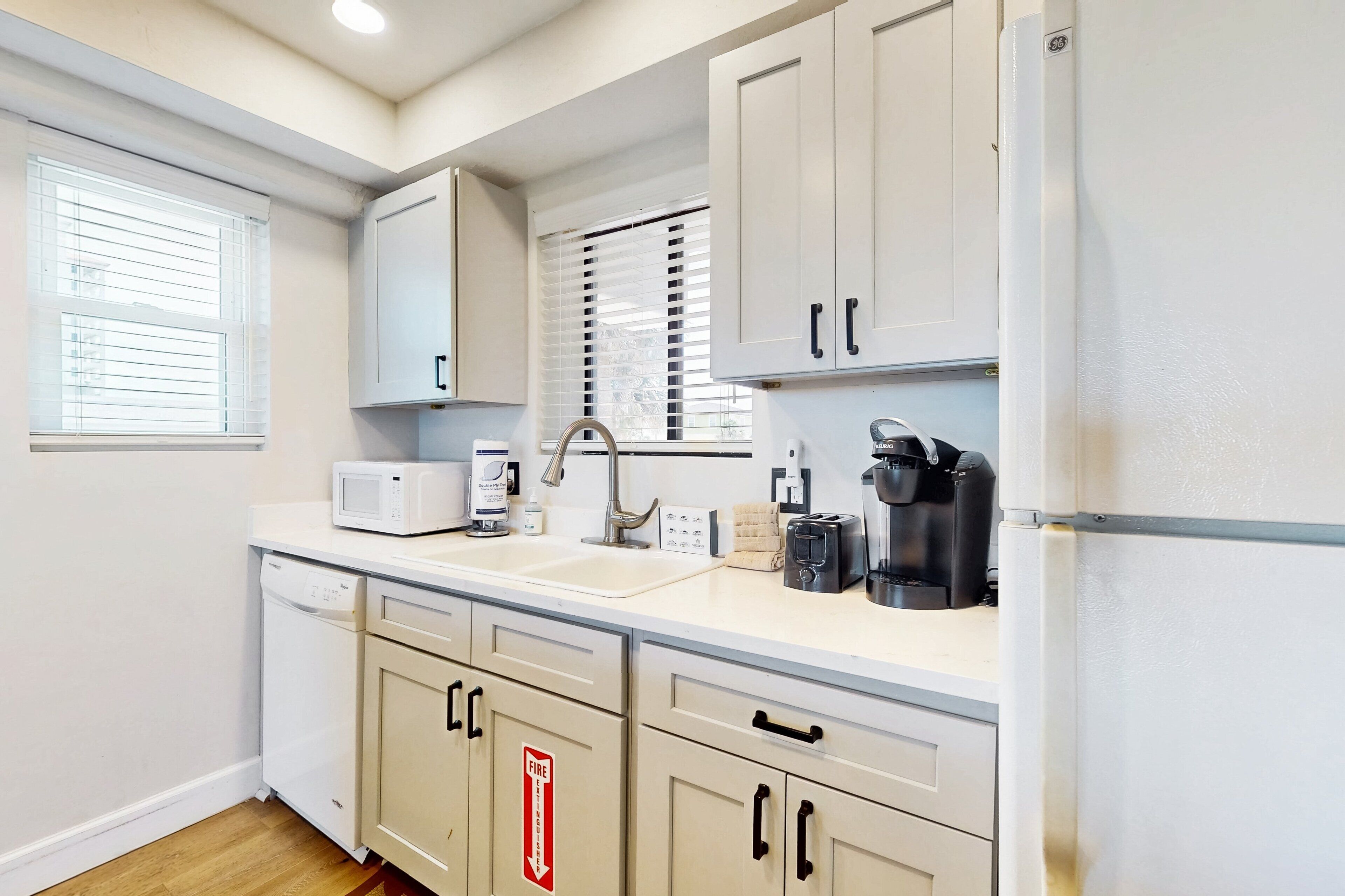 A modern kitchen with white cabinets, a dishwasher, a coffee maker, and a toaster.