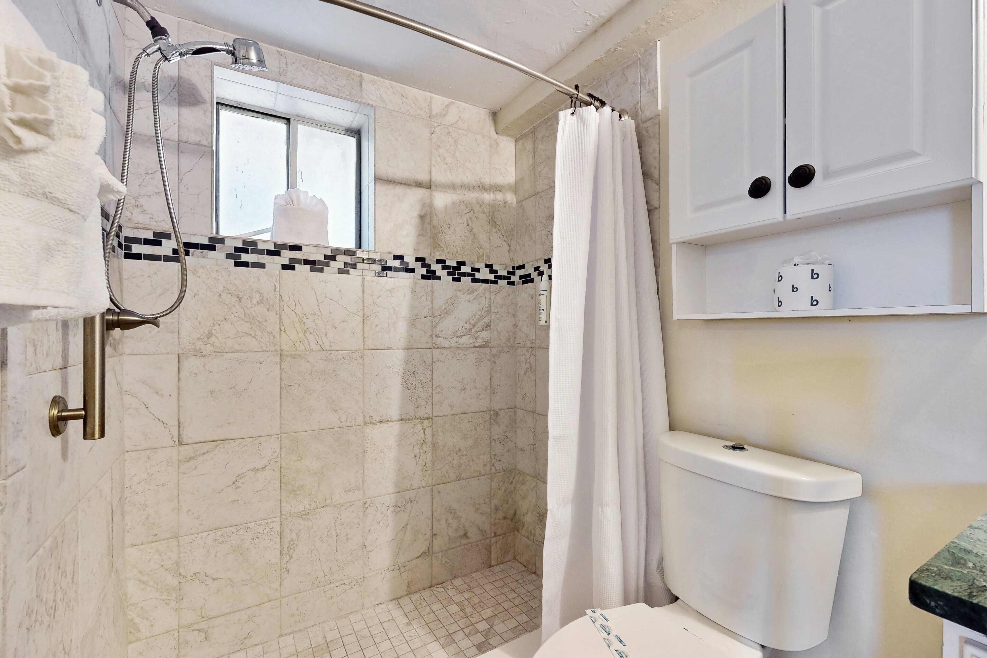 Une salle de bain avec une douche, des toilettes et une fenêtre.