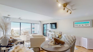 Ein modernes Wohnzimmer mit einem runden Tisch, weißen Sofas und einem großen Fenster mit Blick auf die Stadt.