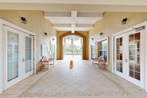A covered corridor with tiled flooring, white-framed glass doors, and wooden benches. - Immaculate Townhome in Upscale Community w/ Pool & Balcony - Near Beach (Palm Coast)