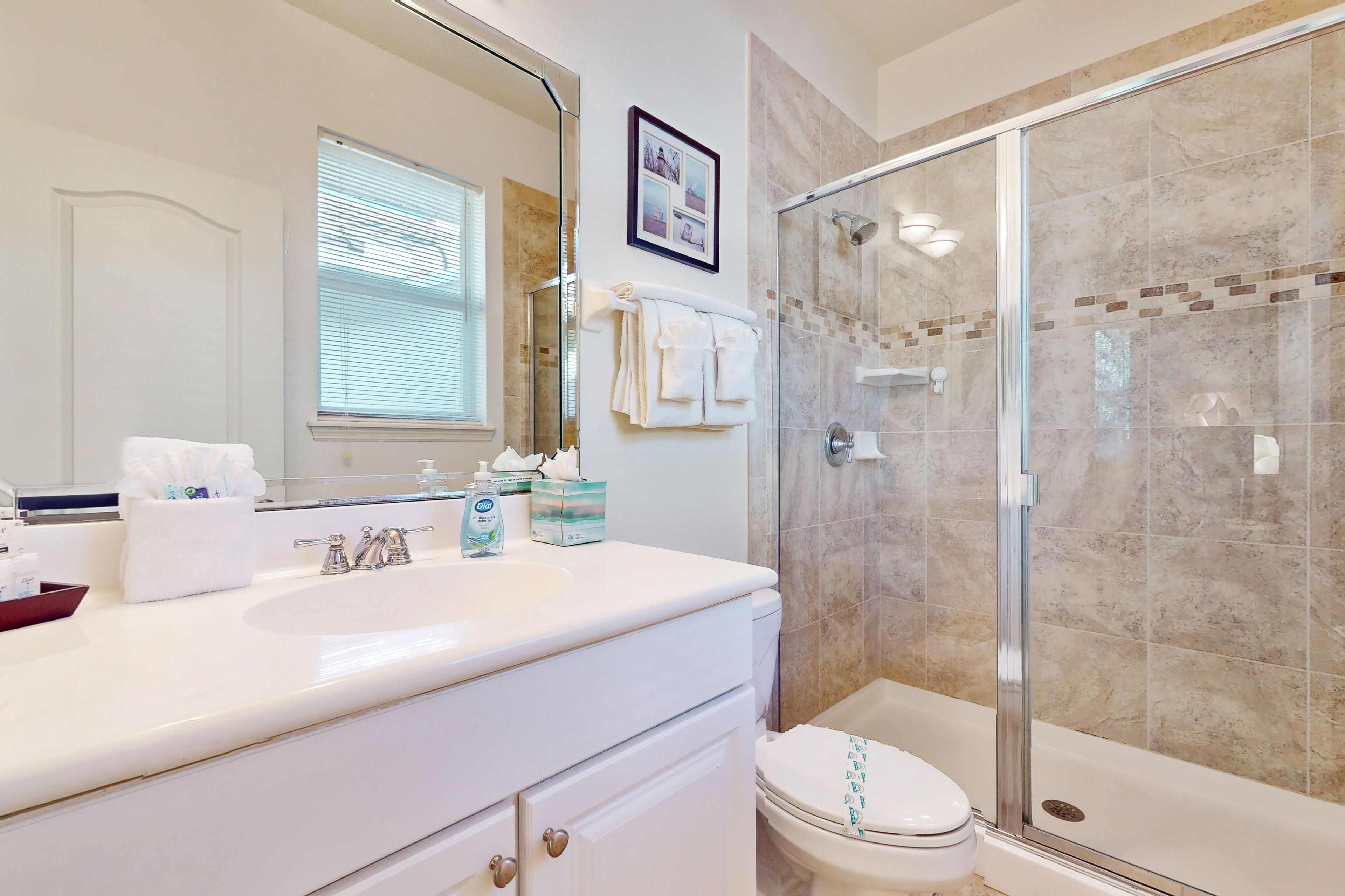 A bathroom with a glass-enclosed shower, a white sink, and a toilet.