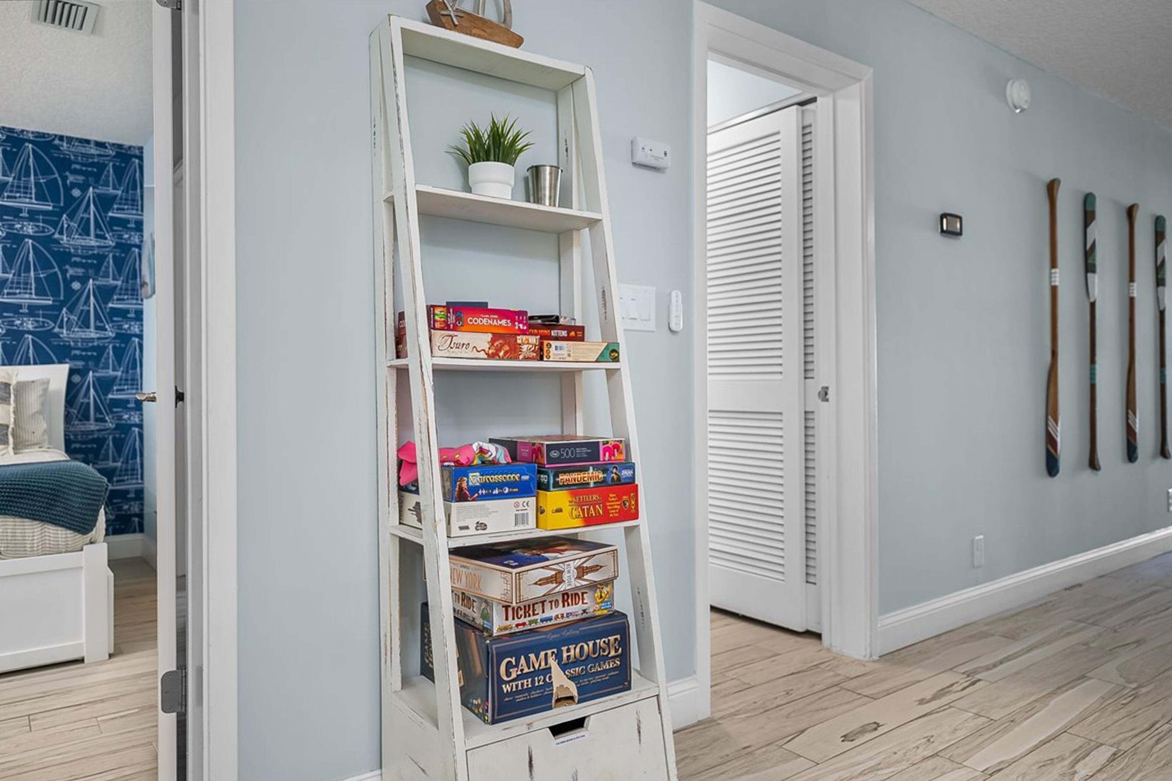 A room with a bookshelf, a bed, a door, and a wall with skis.