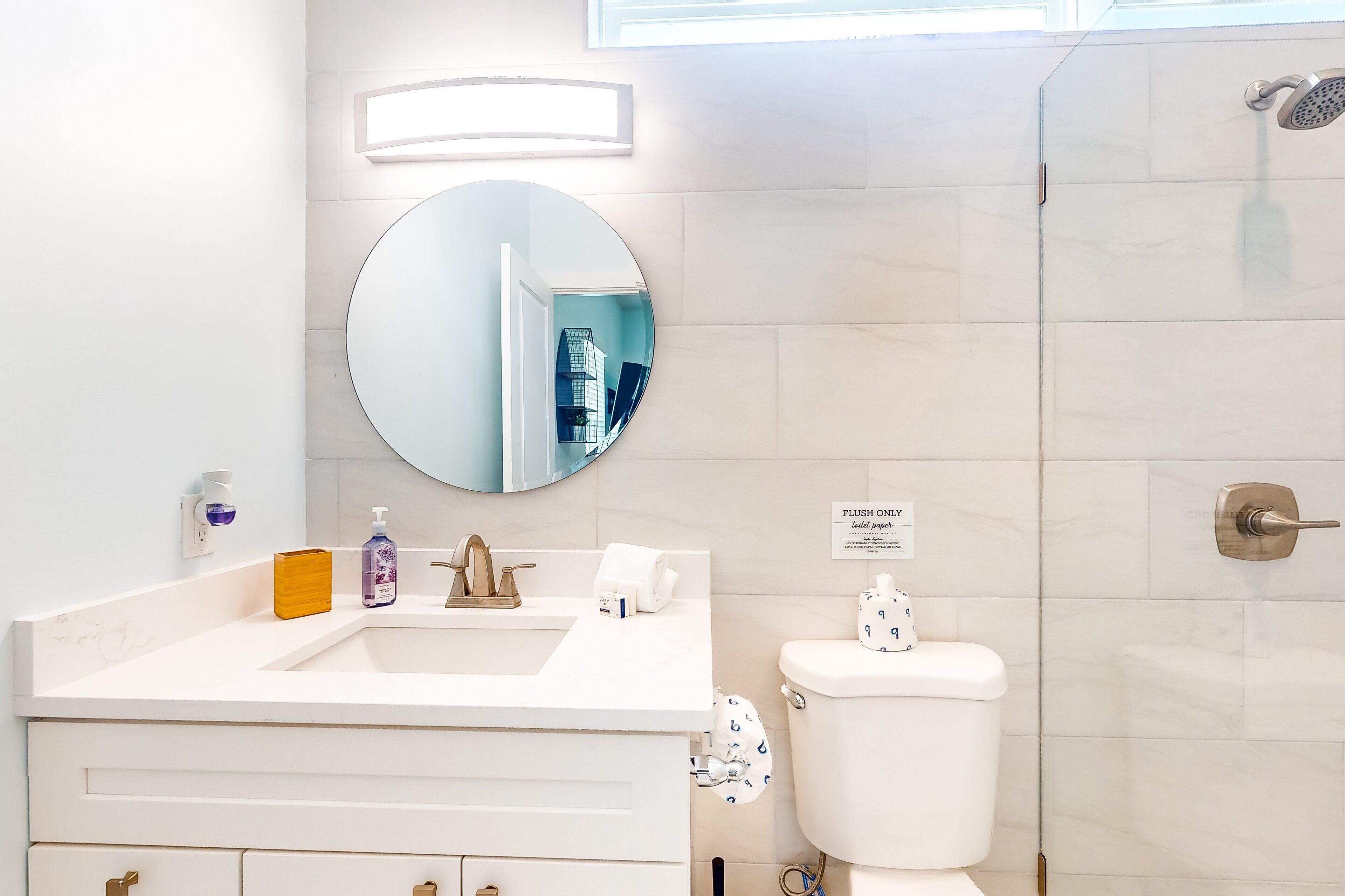 Un baño moderno con lavamanos, espejo y inodoro blancos.