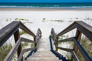 Eine Holztreppe führt zu einem Strand mit freiem Blick auf das Meer.