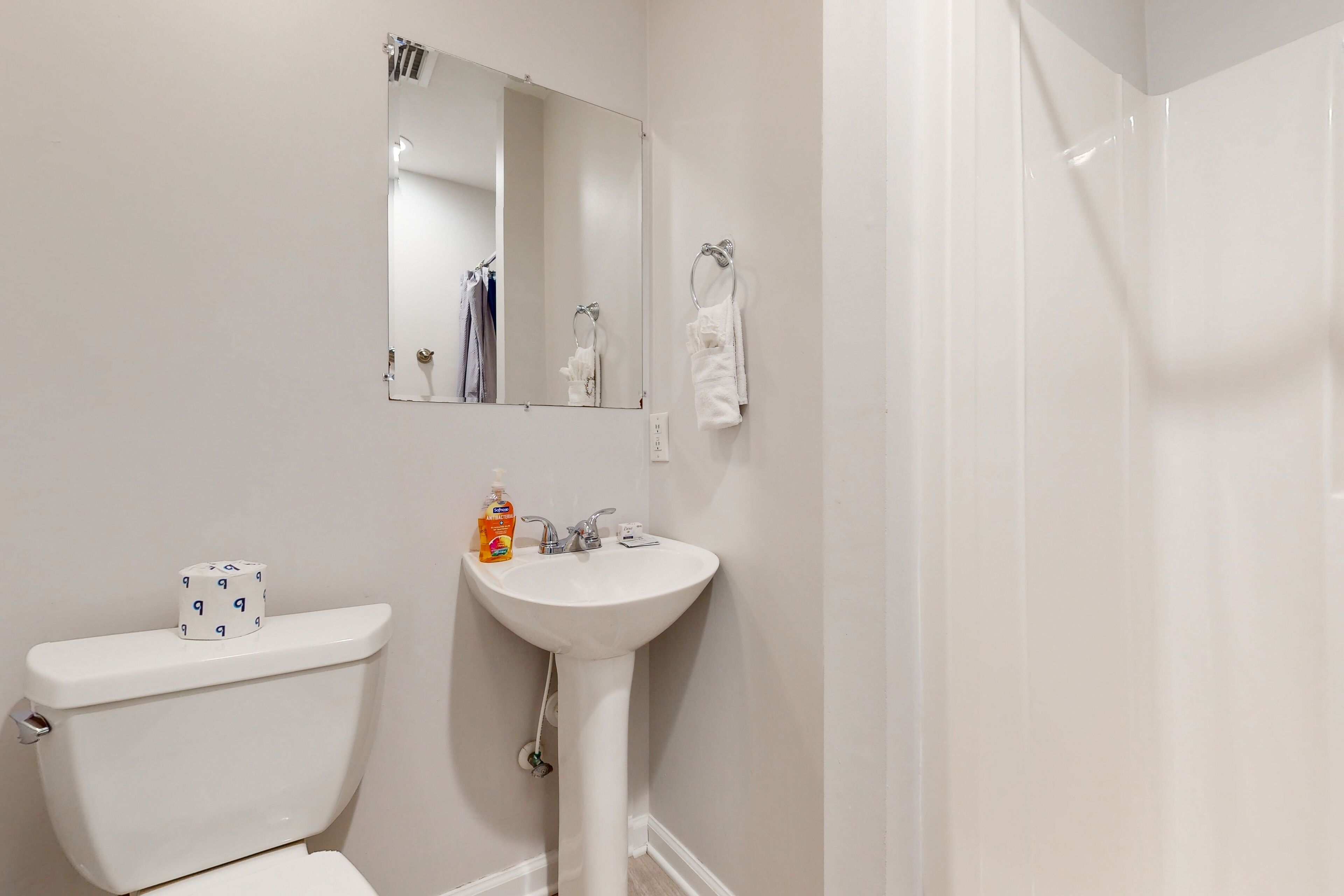 Une salle de bain équipée de toilettes, d’un lavabo, d’un miroir et d’une douche.