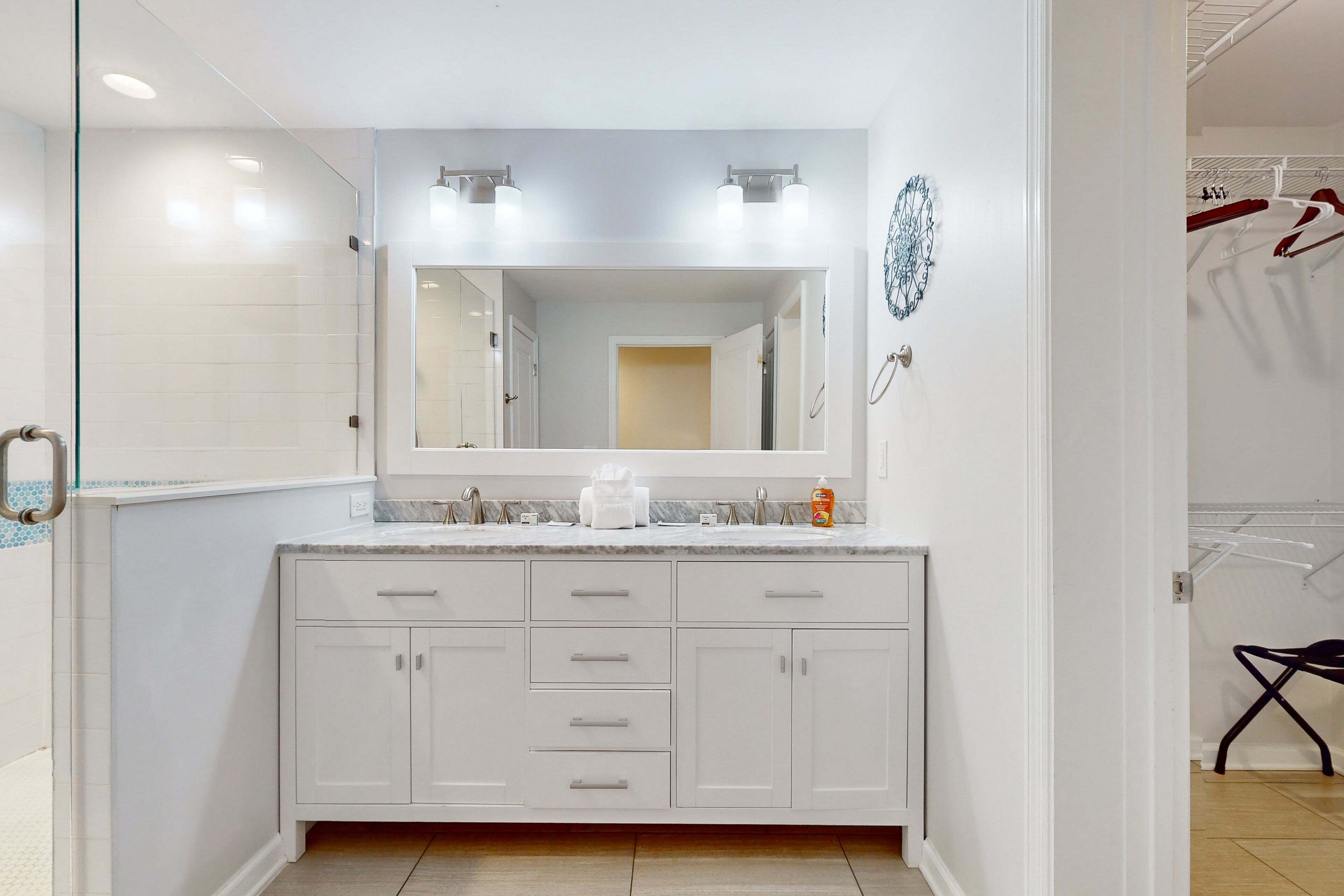 A bathroom with a white vanity, a large mirror, and a shower area.