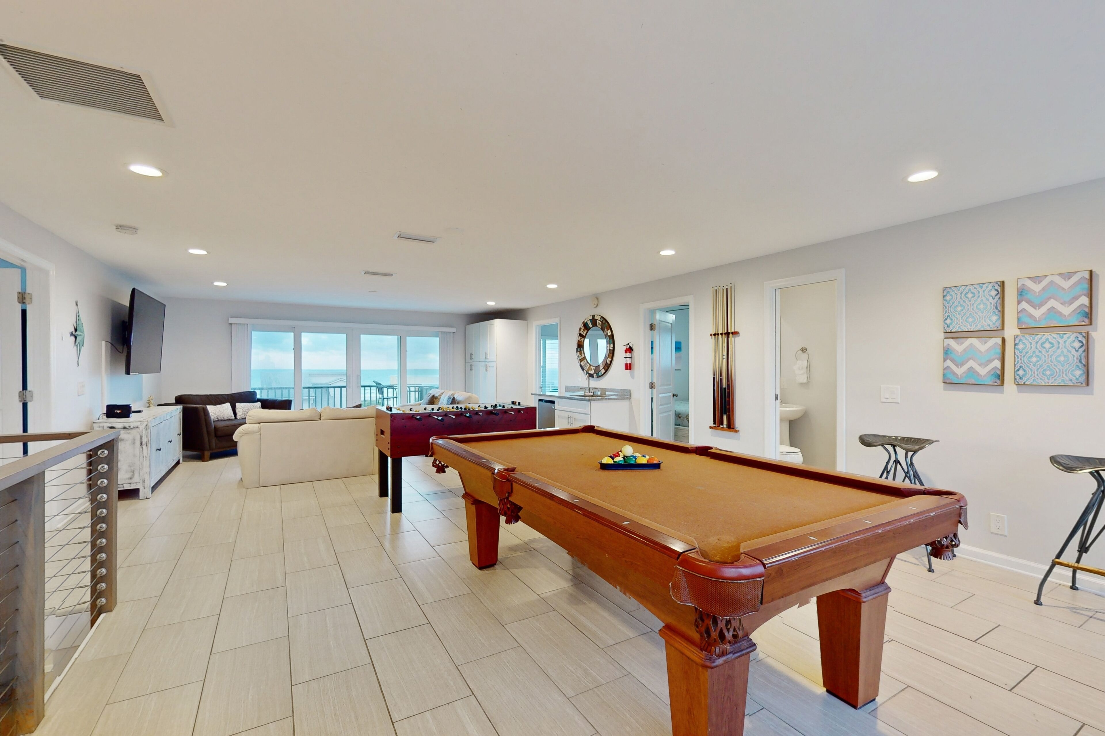 A spacious living area with a pool table, a sofa, and a foosball table.