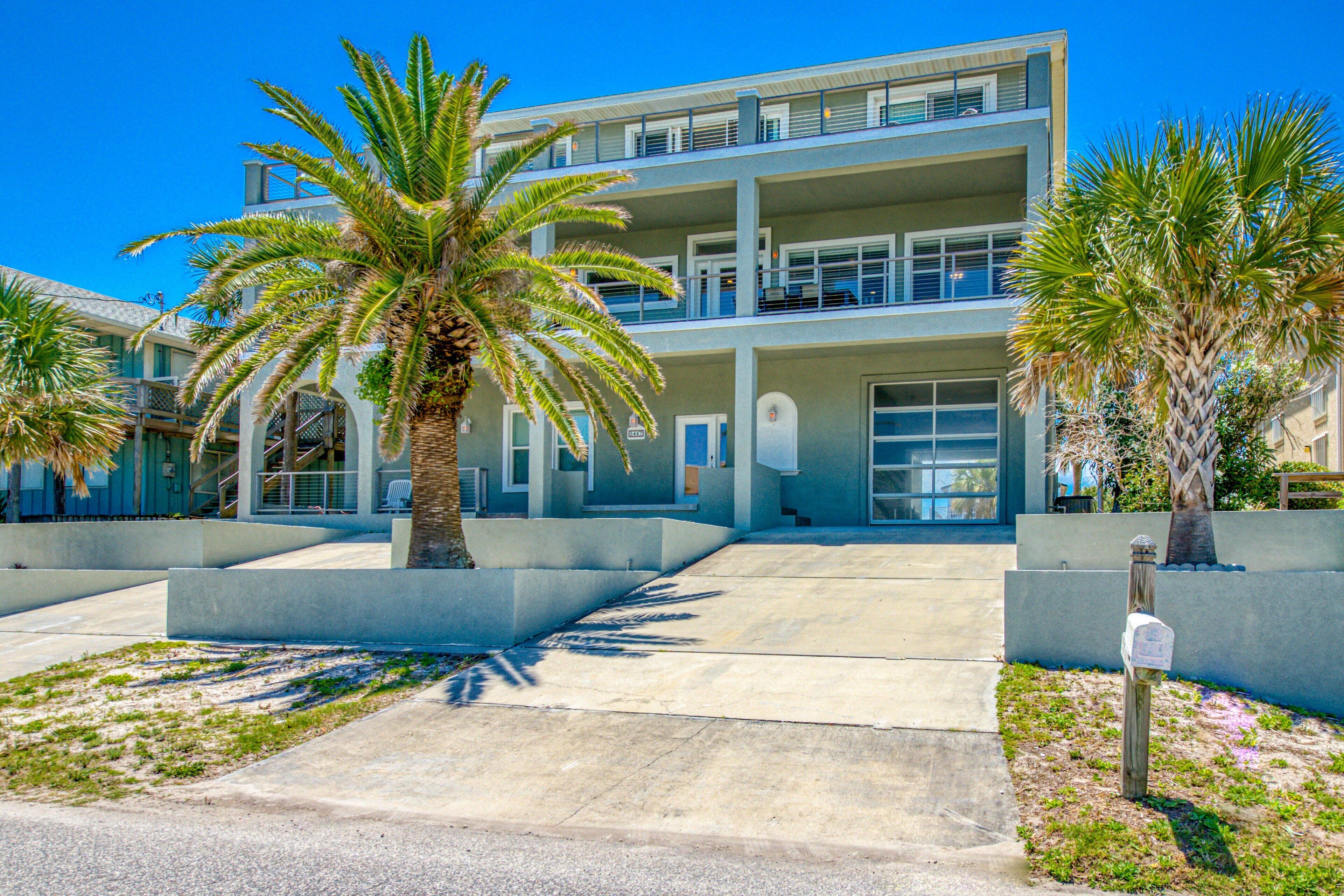 A modern multi-story building with balconies, palm trees, and a clear sky.
