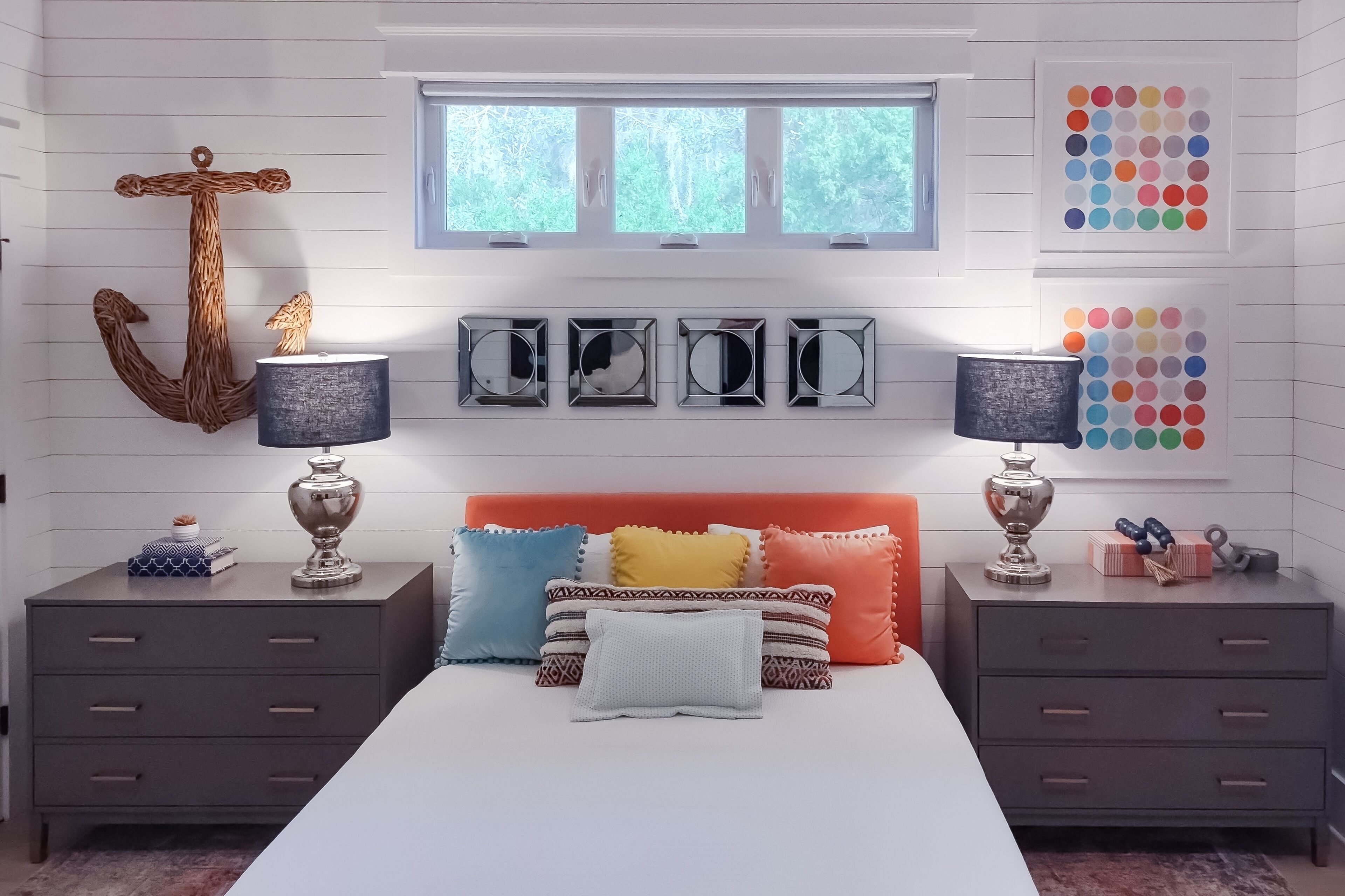 A bedroom with a bed, two nightstands, a window, and wall decorations.