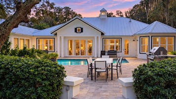 Uma casa com piscina, móveis de pátio e área de churrasco.