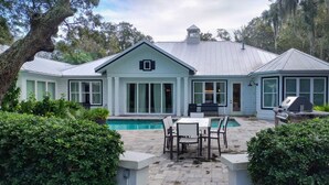 A house with a swimming pool, outdoor seating, and a well-maintained garden. - Lakefront Home With Private Pool & Outdoor Space for Entertaining (St. Simons Island)