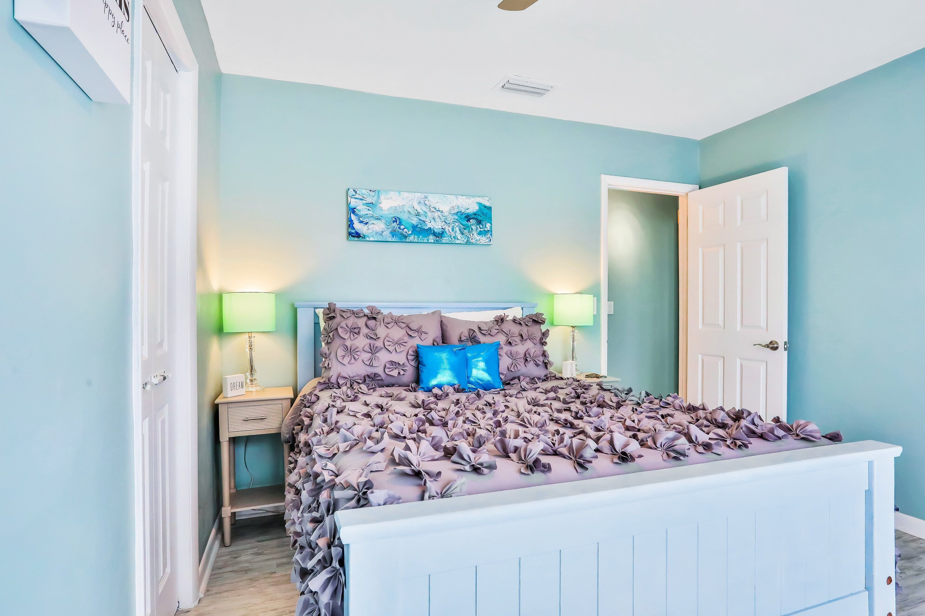 A bedroom with a bed, nightstands, a door, and a ceiling fan.