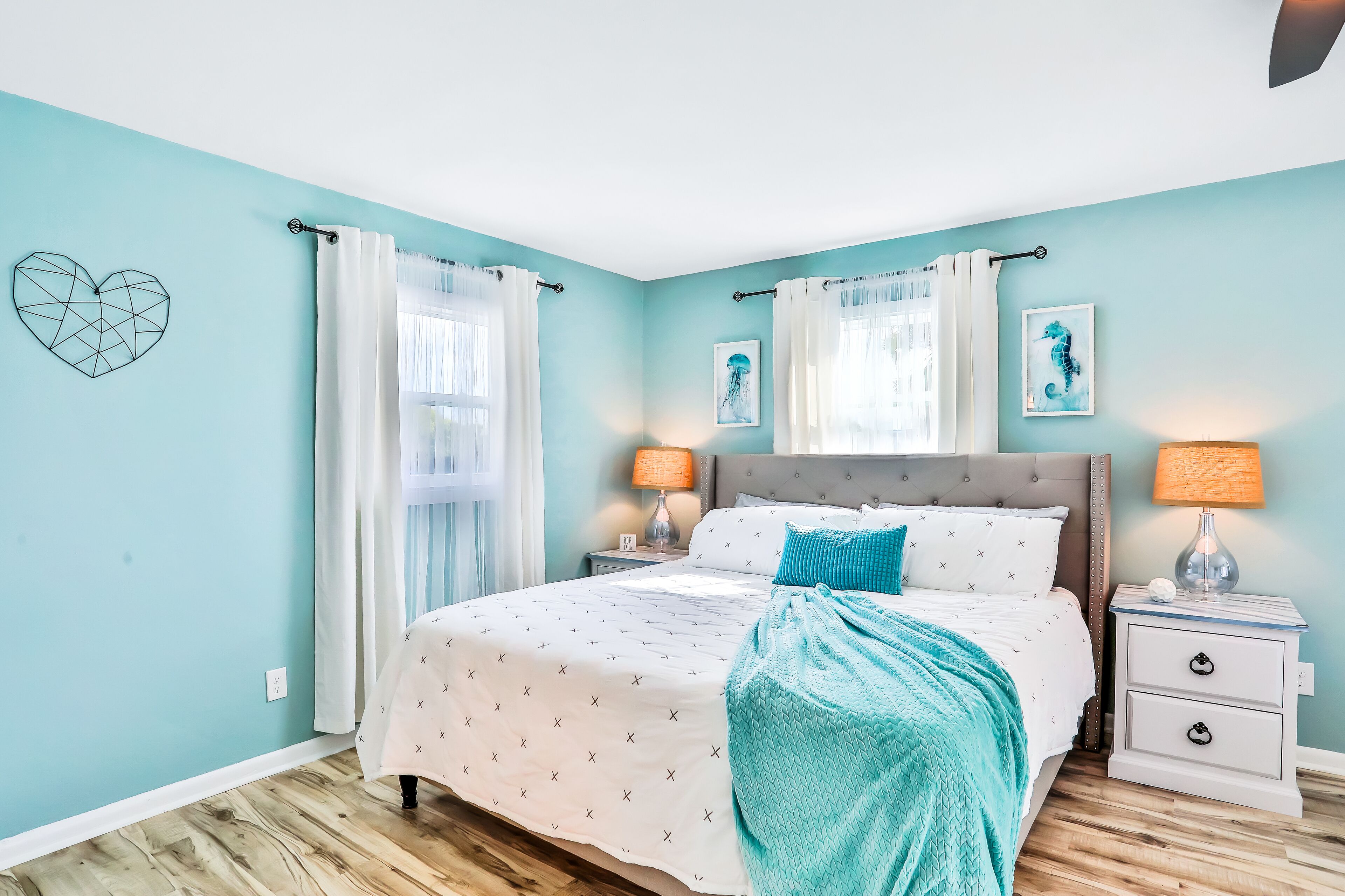 A bedroom with a bed, nightstands, and a wall with artwork.