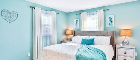Un dormitorio con cama, mesitas de noche y una pared decorada con obras de arte.