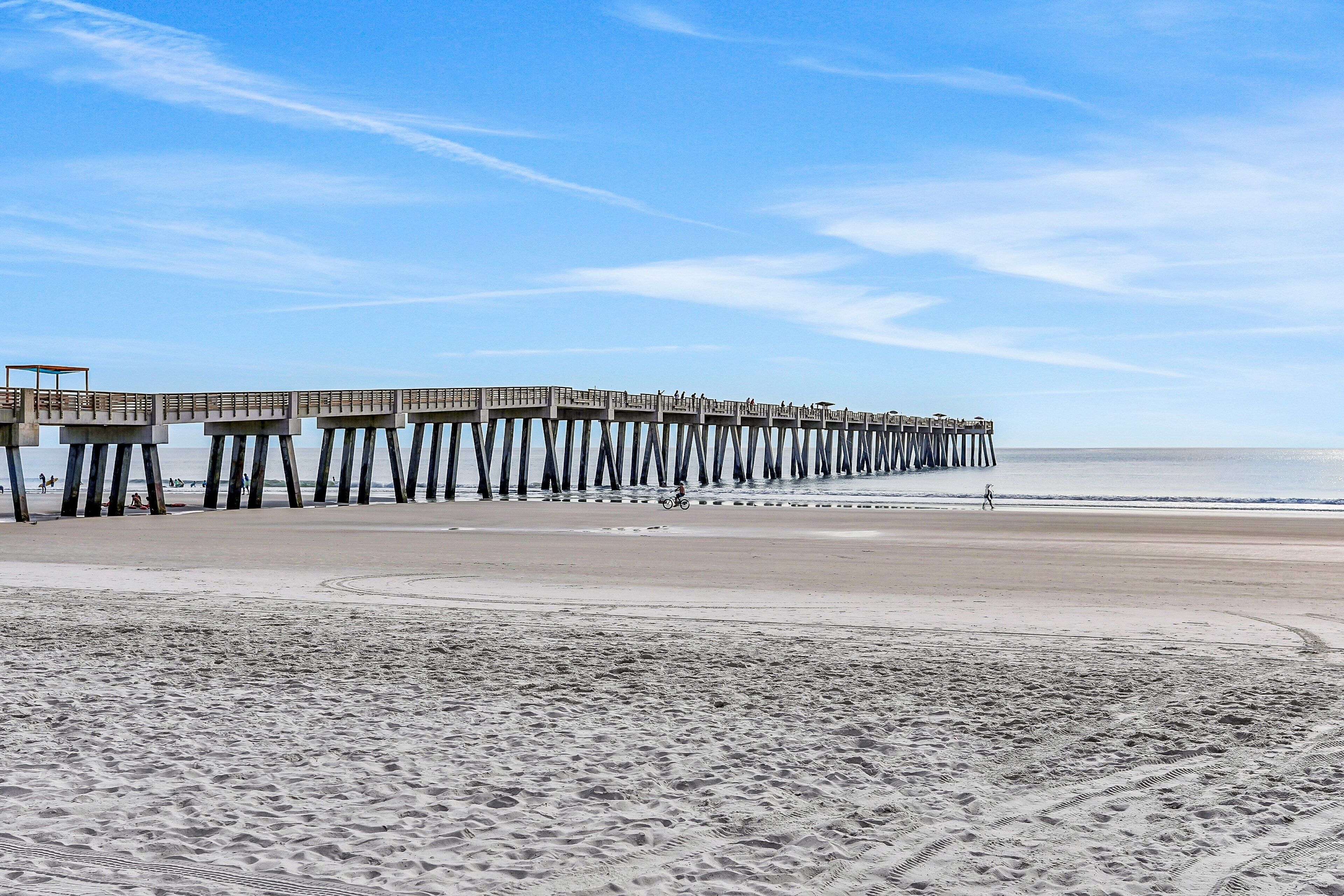 A pier extending into the ocean with a sandy beach in the foreground.