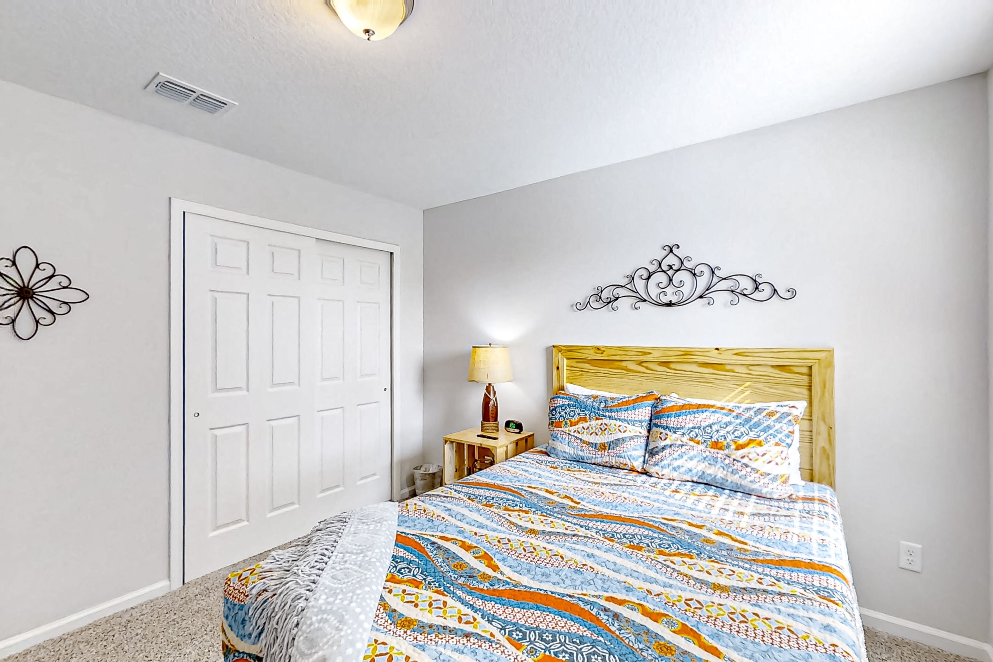 Un dormitorio con cama, mesita de noche, lámpara, puerta y decoración mural.