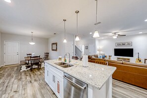 Una cocina moderna con encimera de granito, electrodomésticos de acero inoxidable e iluminación colgante.