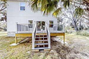 Una casa blanca con un porche de madera y una escalera que lleva a un balcón.