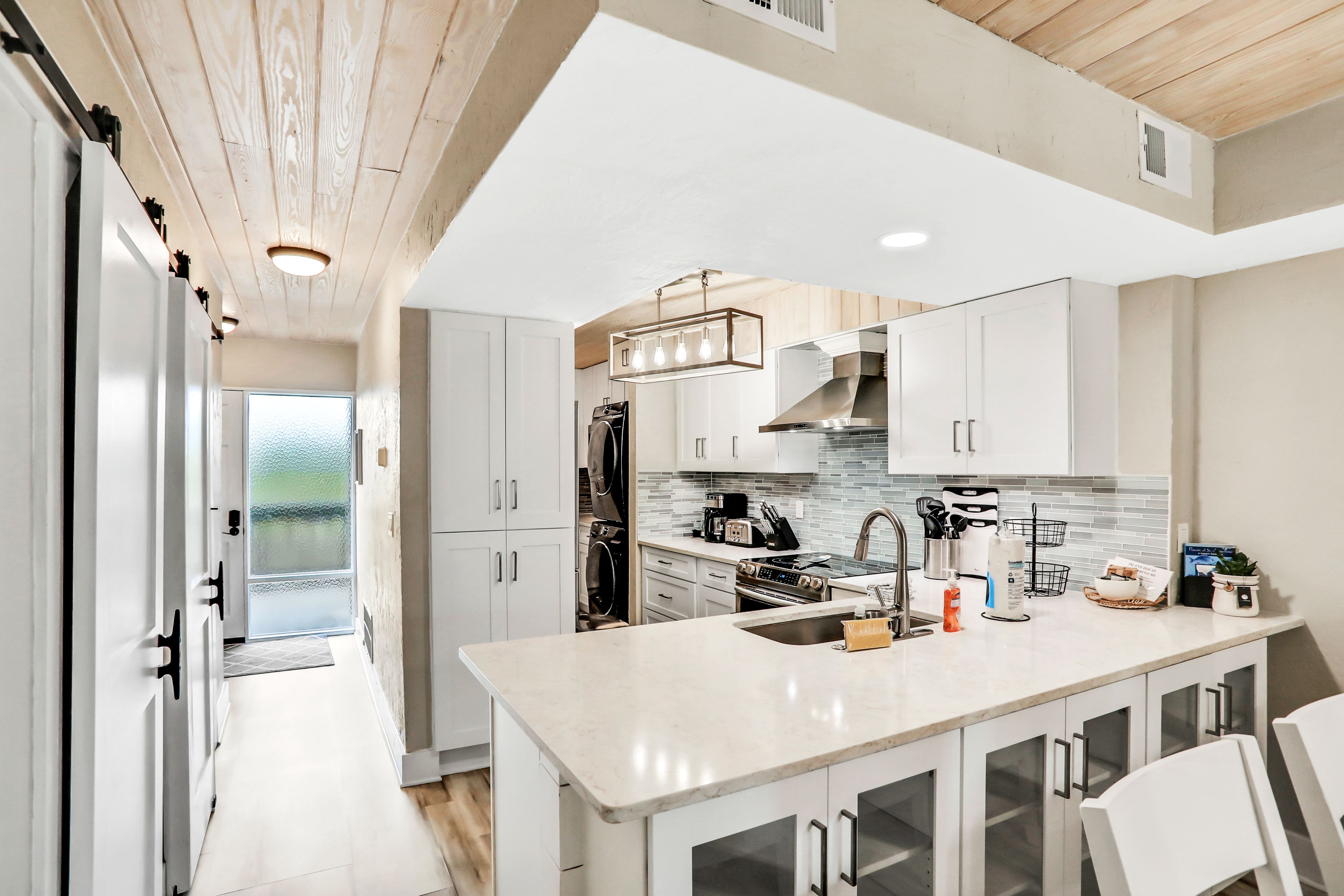 A modern kitchen with white cabinets, a large island, and a stainless steel range hood.